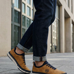 Lifestyle shot of the bugatti Vanadium Yellow comfort low-top sneakers on a person wearing dark jeans with rolled cuffs.