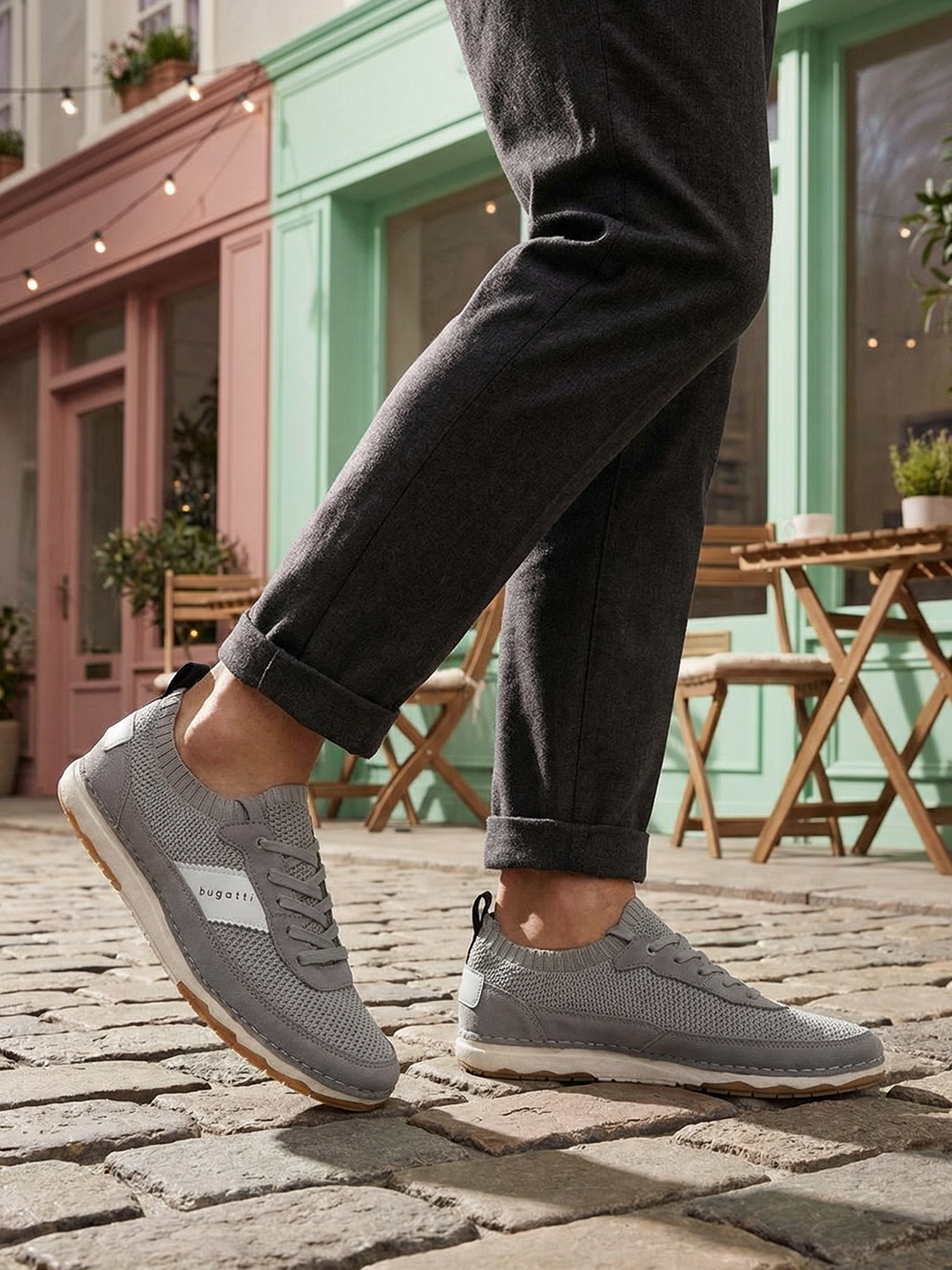 Grey low top sneakers by bugatti with a knit texture and white accent stripes, worn with dark grey pants.