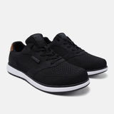 Black mid-top sneakers by bugatti with white midsoles and brown accent on heel.