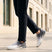 Cropped lifestyle view of bugatti Nubola white athleisure sneakers with a gradient design and white soles, worn with black trousers.
