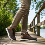 Brown and tan comfort casual boots by Bugatti, styled with a white midsole and worn with khaki trousers on a wooden boardwalk.
