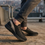 Lifestyle image of bugatti Soa black mid-top sneakers with a grey accent, paired with grey joggers.